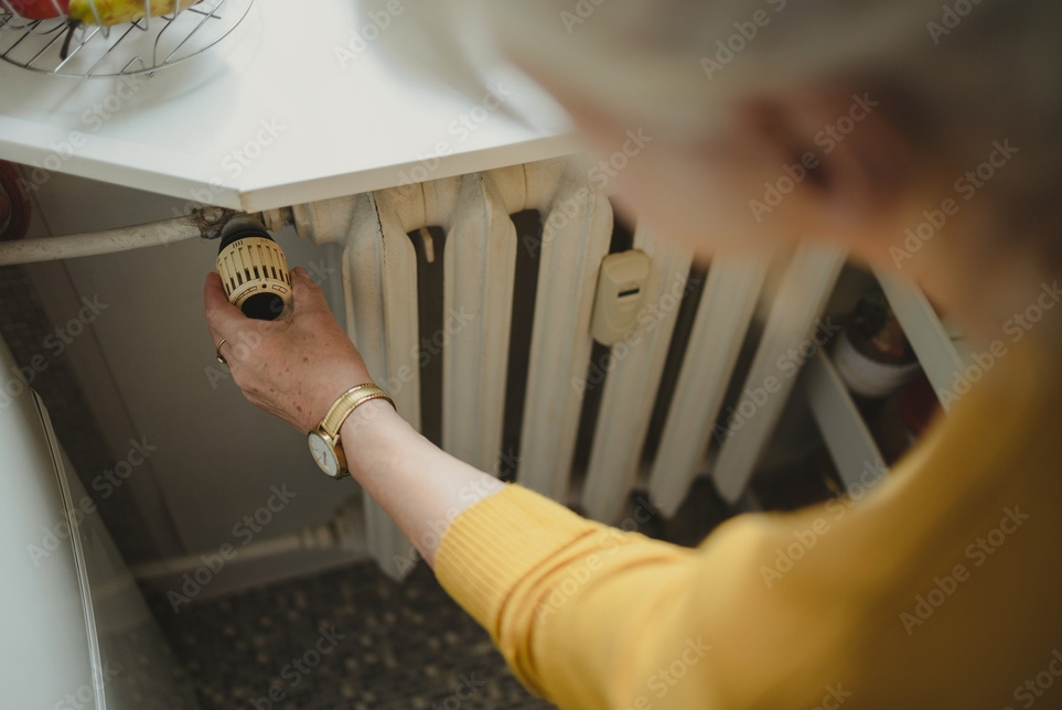 Person adjusting heating controls on a radiator